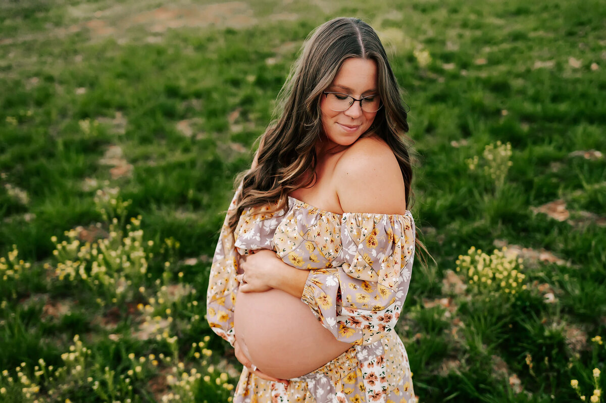 maternity photo in Branson MO of pregnant mom in floral dress hugging baby bump