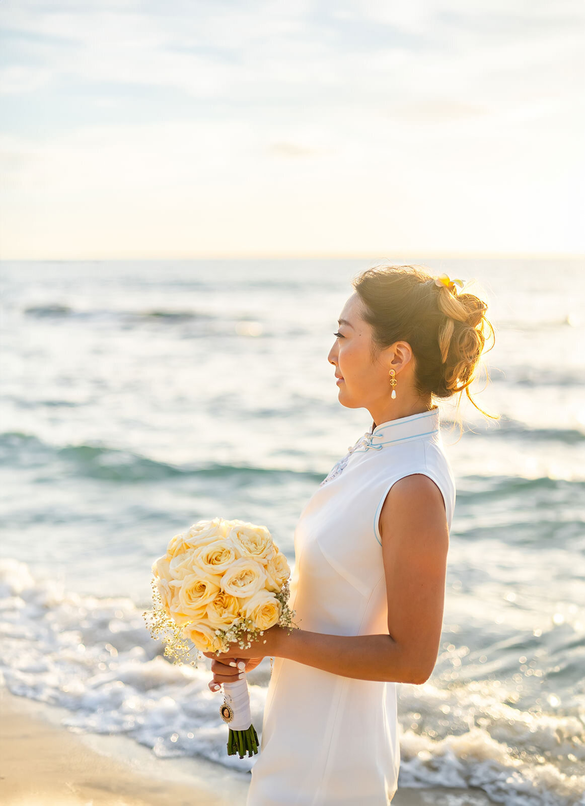 ethereal bride with rose bouquet at the beach  gazing out  at the ocean