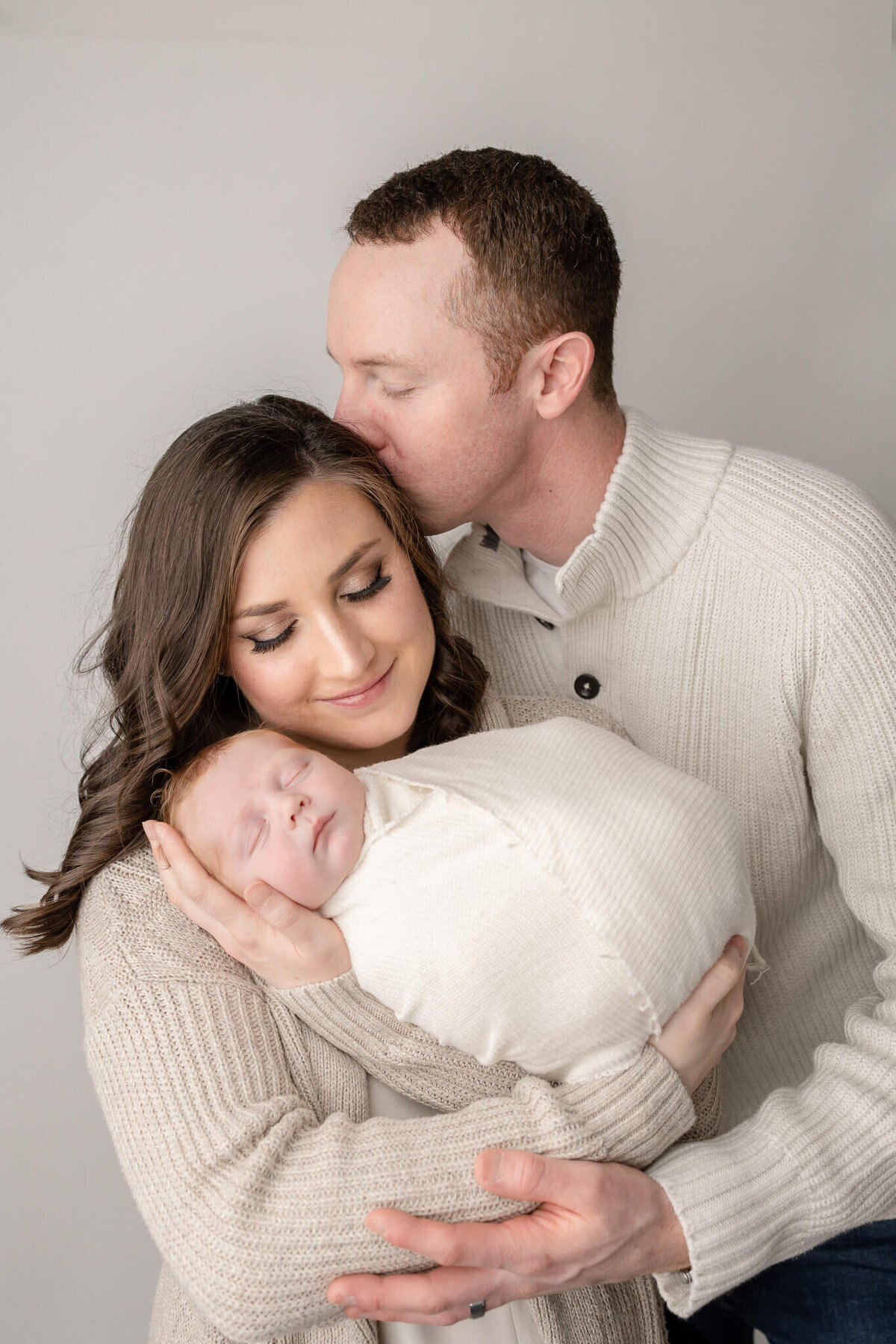 dad kissing mom's head for newborn photography  session