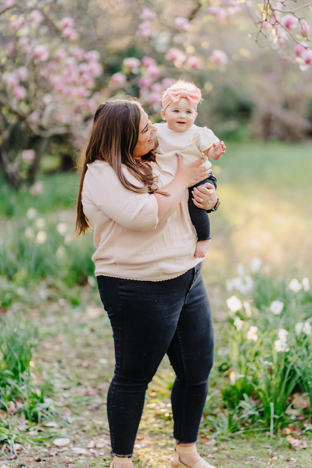 mother with baby standing in front of a cherry blossom tree