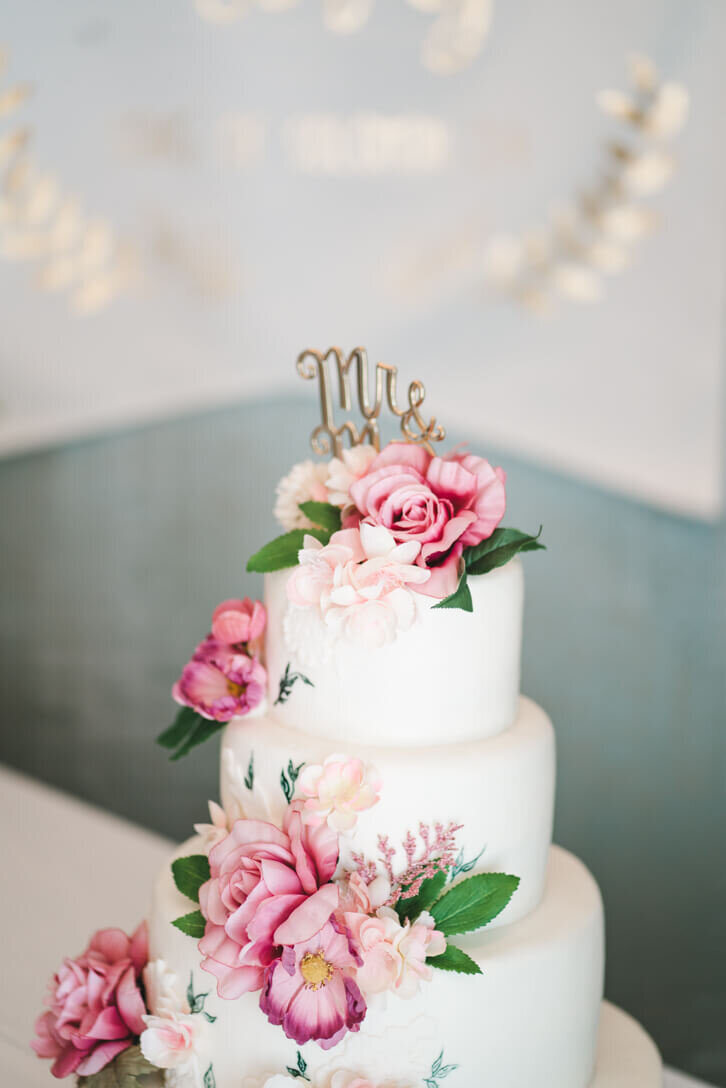 beautiful three tiered wedding cake with roses and greenery.
