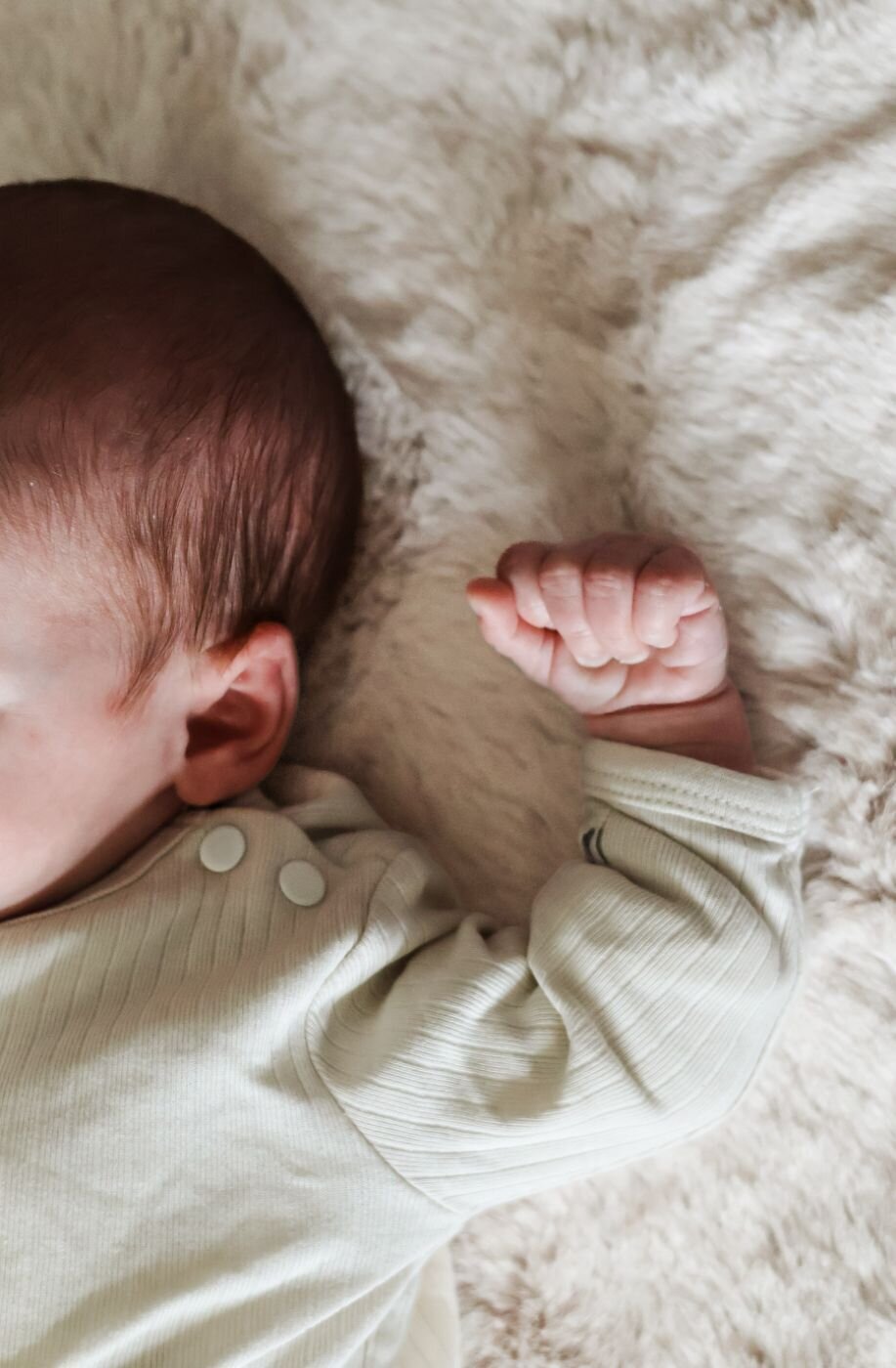 pasgeboren hoofdfoto terwijl de handen dicht bij elkaar zijn in witte kleding 