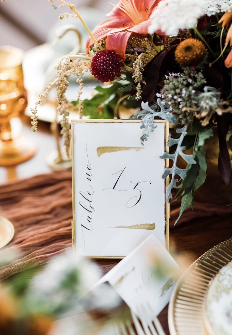 Custom table number calligraphy with the dinnerwares and floral centerpiece