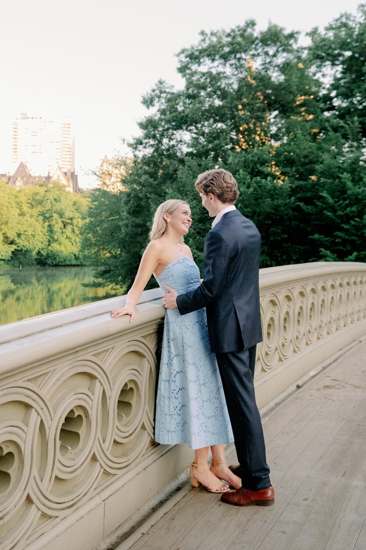 an engaged couple standing on a bridge in Central Park