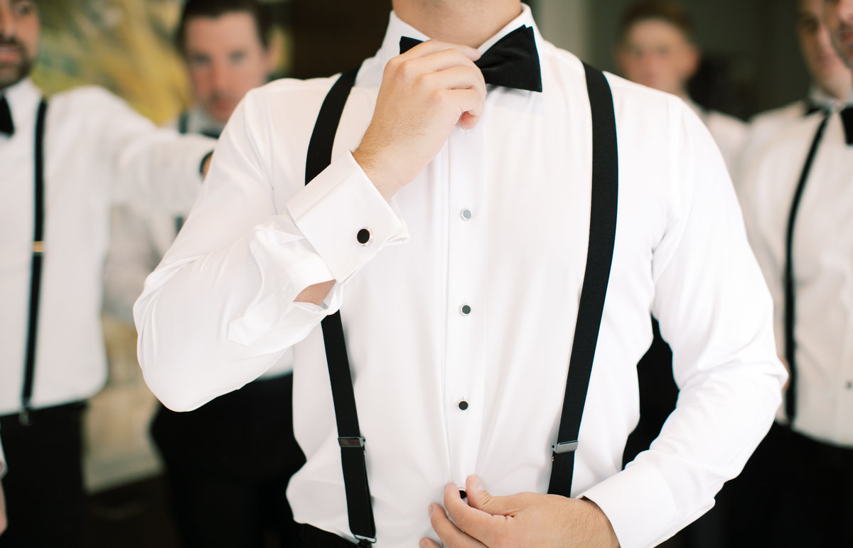 groom adjusting bowtie while getting ready for wedding