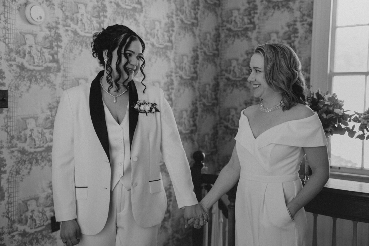 Women hold hands and smile at each other on their elopement day 