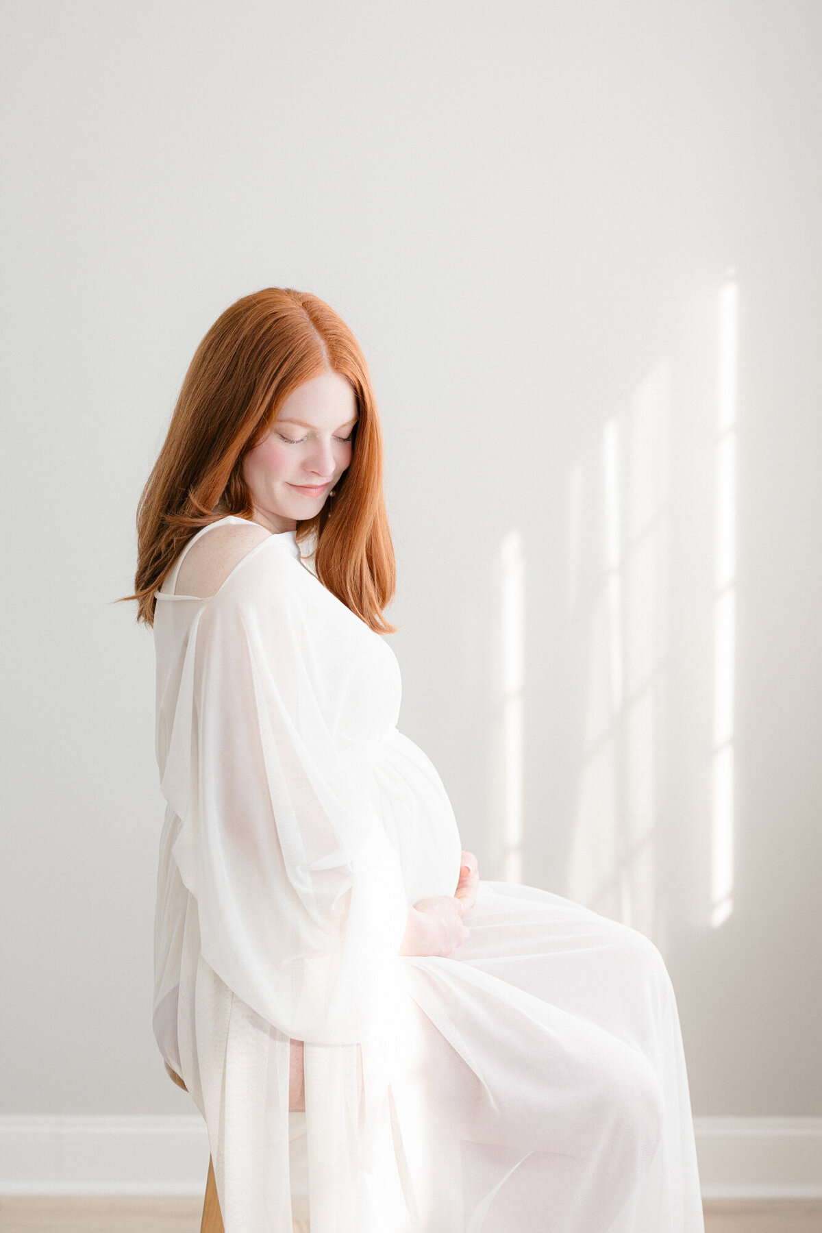 Pregnant mom wearing a white chiffon dress in a Louisville photography studio