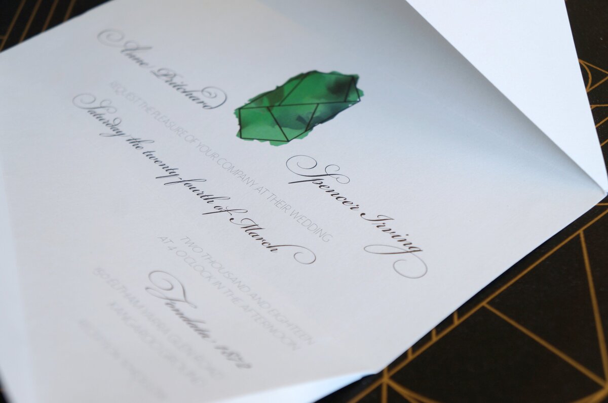 Emerald green graphic inside a white origami wedding invitation with script font