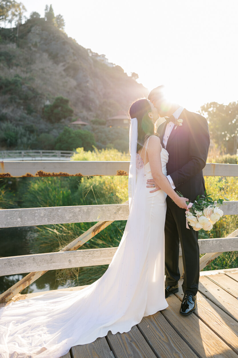 bride and groom kissing on a bridge