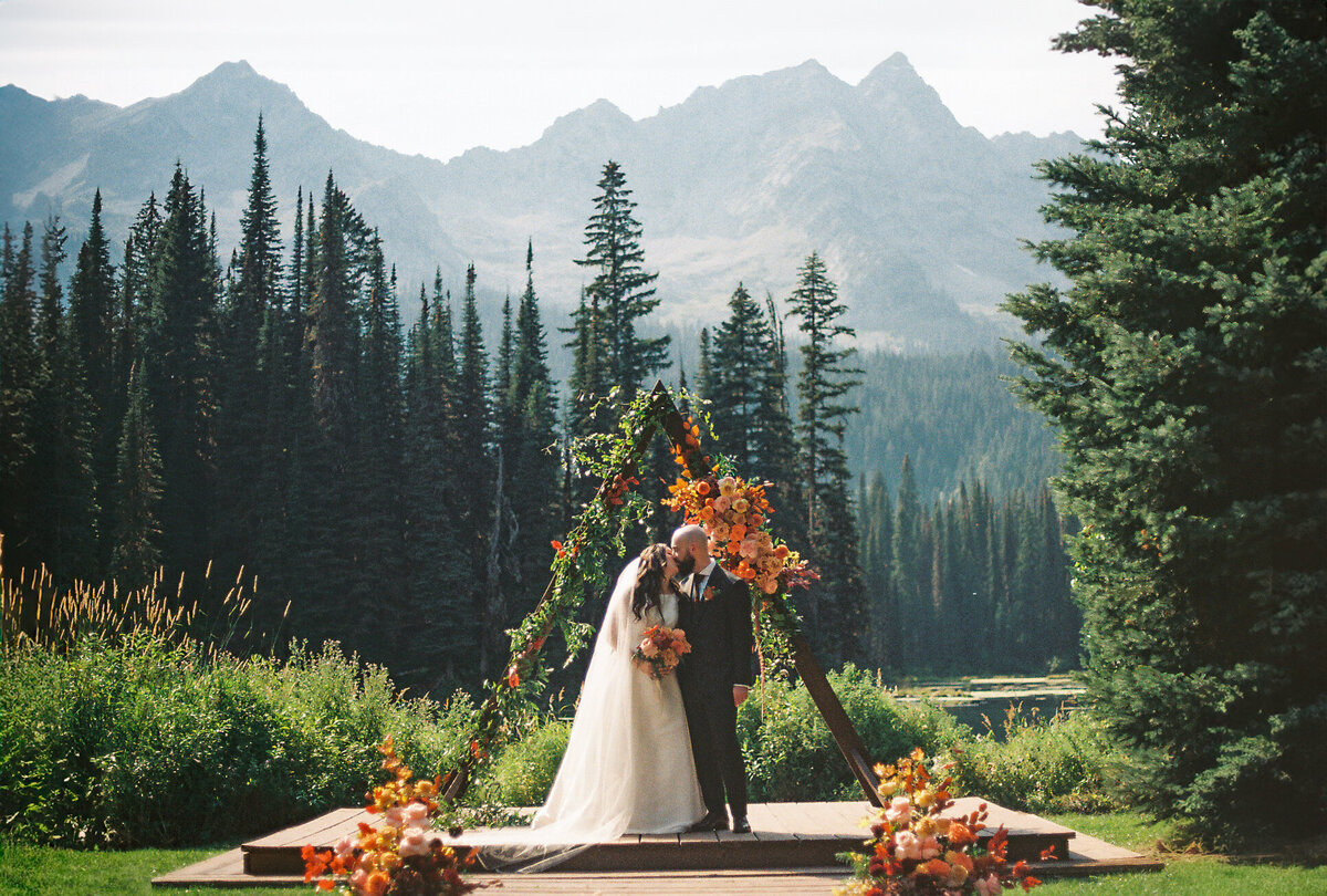 Newly-married couple stand together on rocks overlooking the ocean