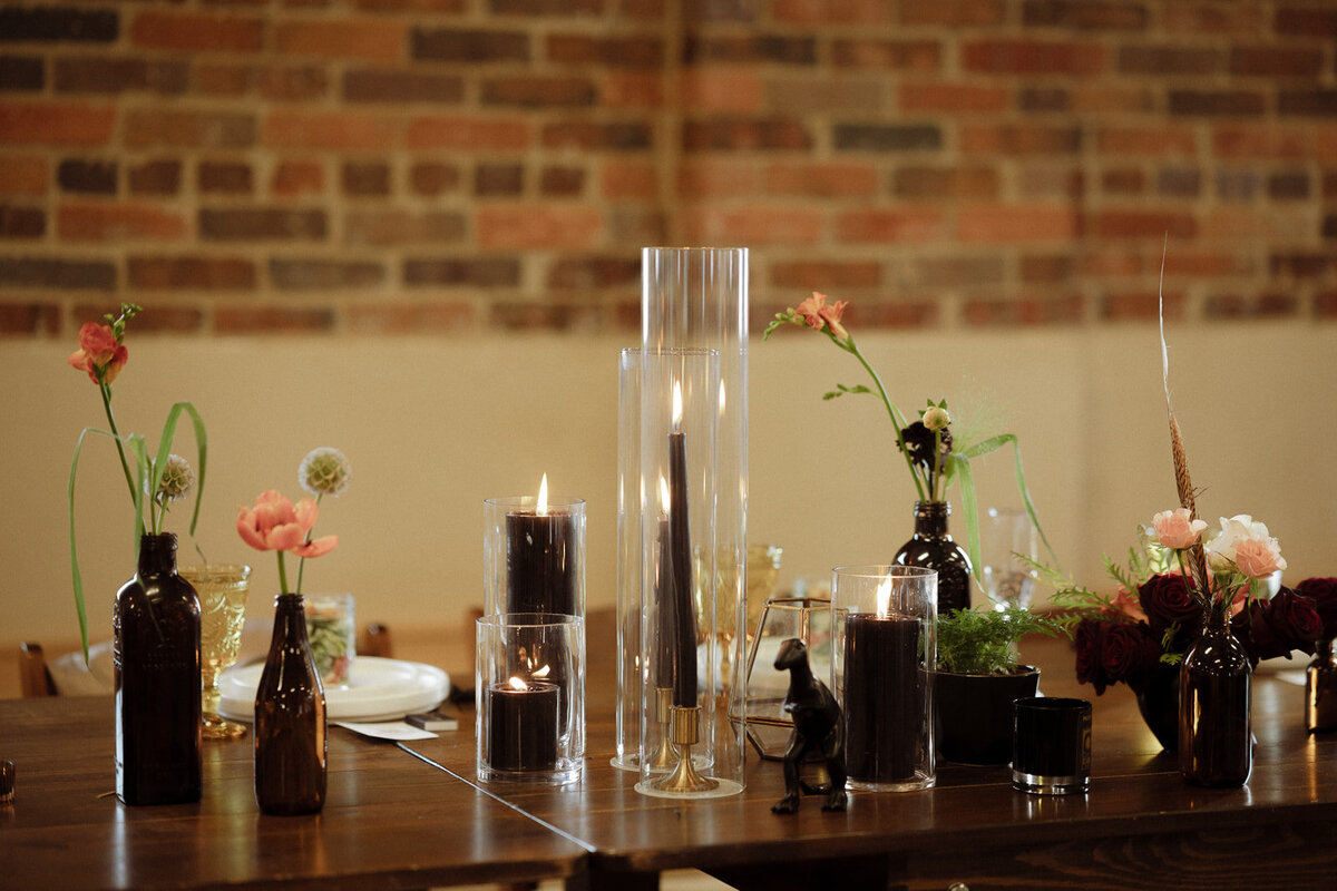 Black candles with peach flowers at a wedding reception.