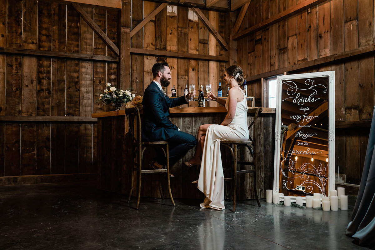 Couple sitting at the bar inside Countryside Barn, rustic, country Lethbridge, Alberta wedding venue, featured on the Brontë Bride Vendor Guide.
