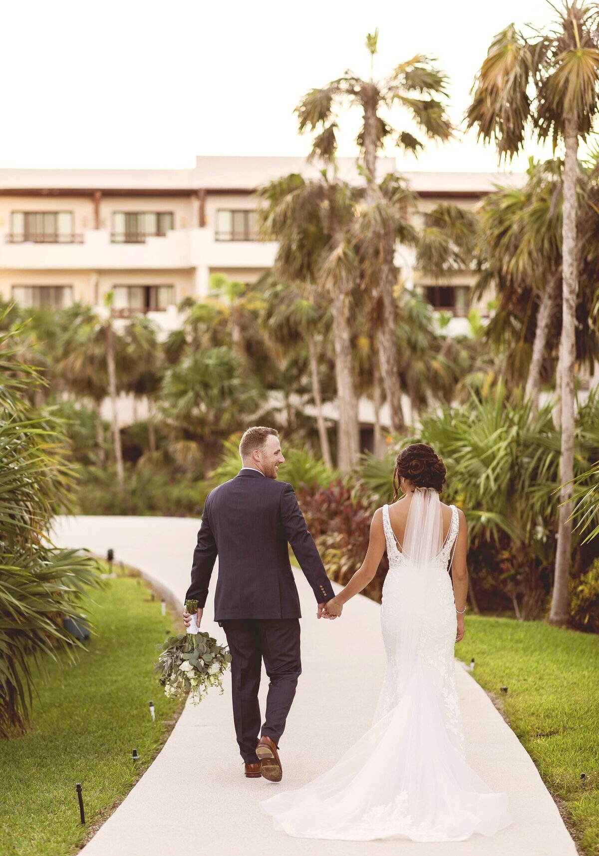 Photo from behind as bride and groom walk down path