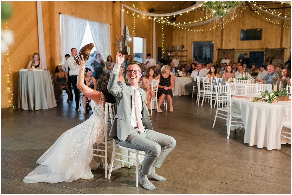 Bride and groom playing the shoe game in the barn at Oak Hills Reception and Event Center