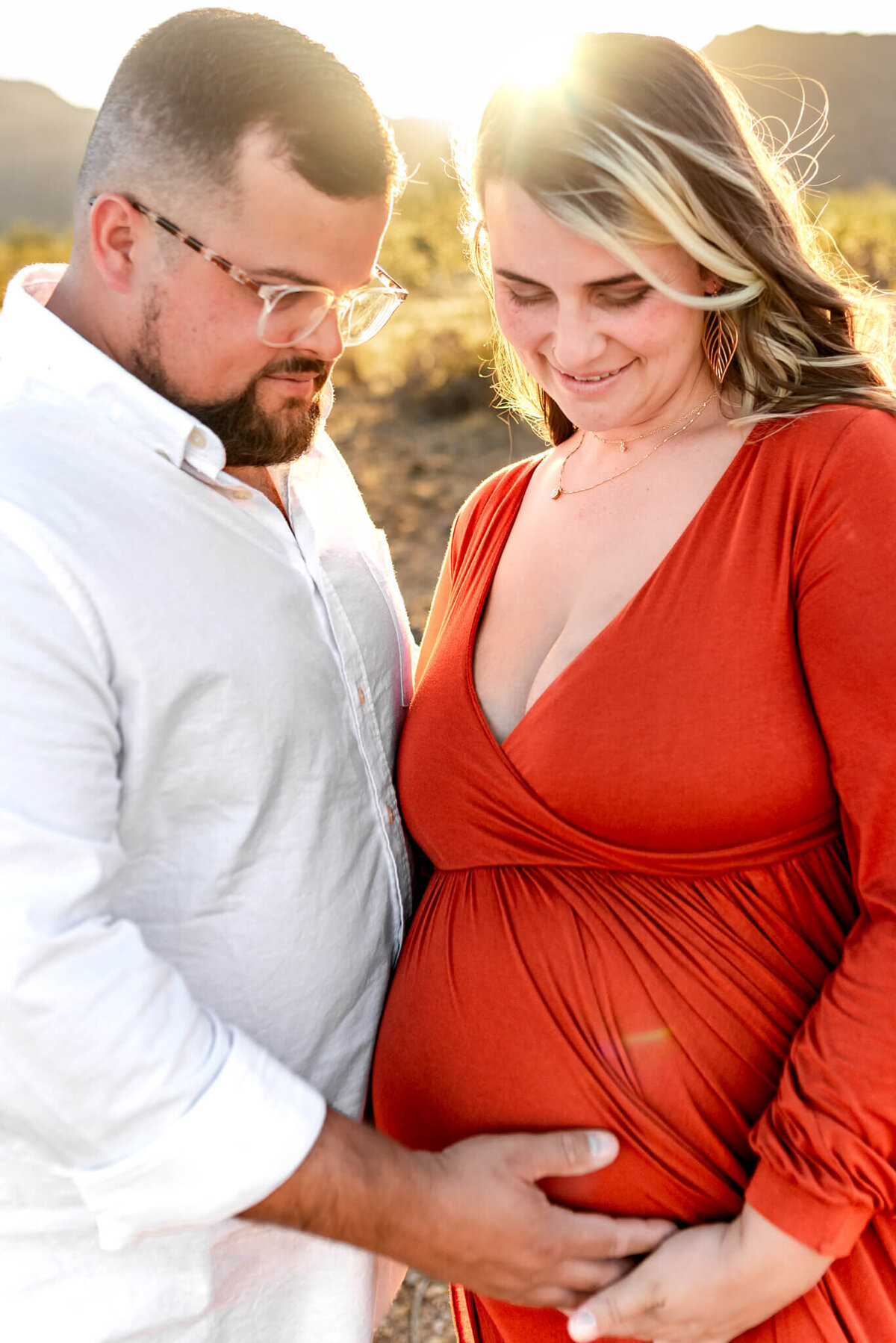 Sweet Arizona parents-to-be standing side by side, touching her baby bump