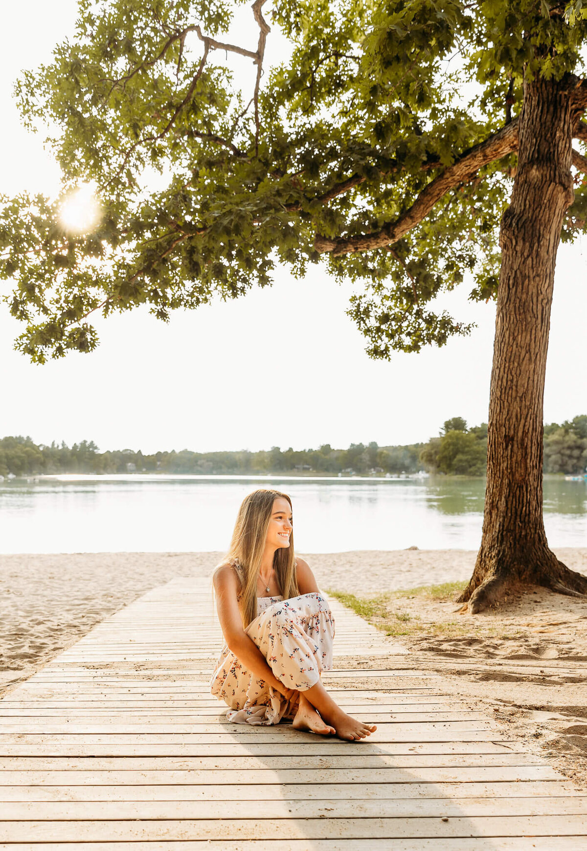 beautiful teenage girl sitting on a beach boardwalk for senior photos