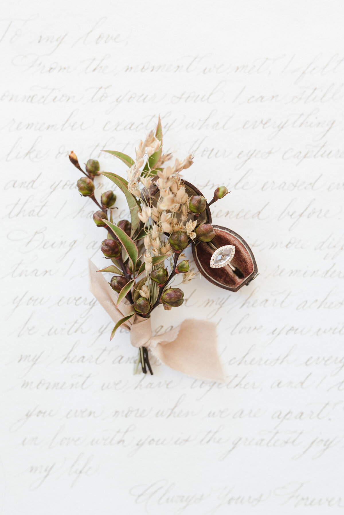 Dried flower boutonniere sitting on top of a white sheet of paper with calligraphy
