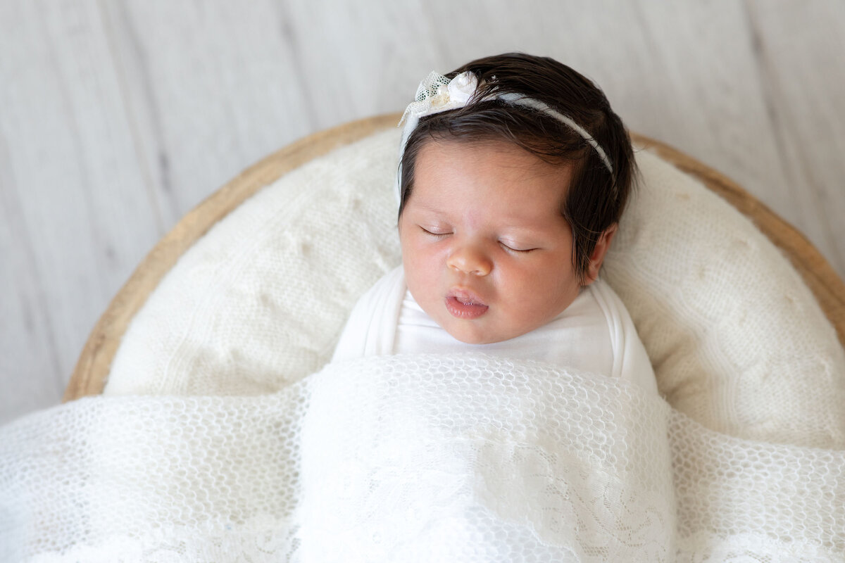 A swaddled newborn baby peacefully sleeping, wrapped snugly in a soft blanket with only their serene face visible.
