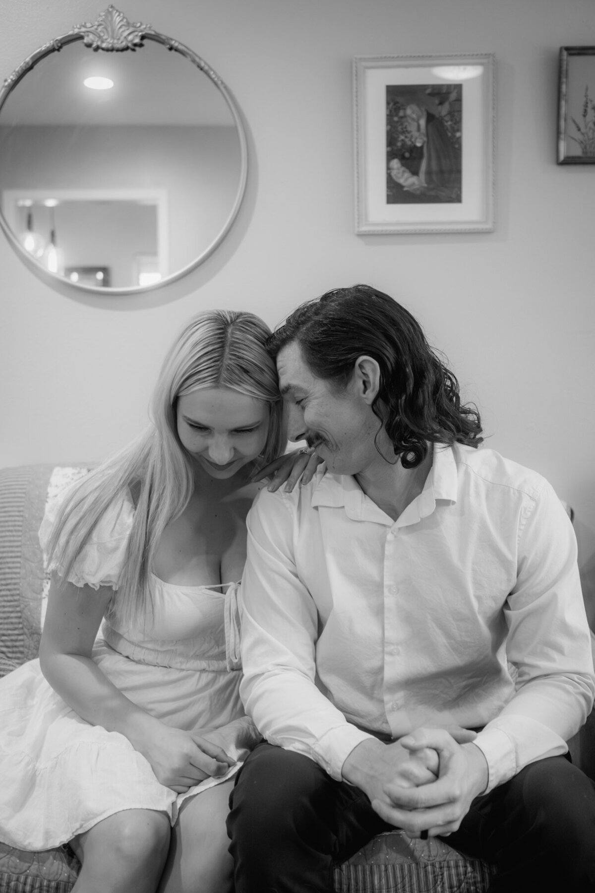 Couple shoot of the parents sitting on a sofa close to each other.