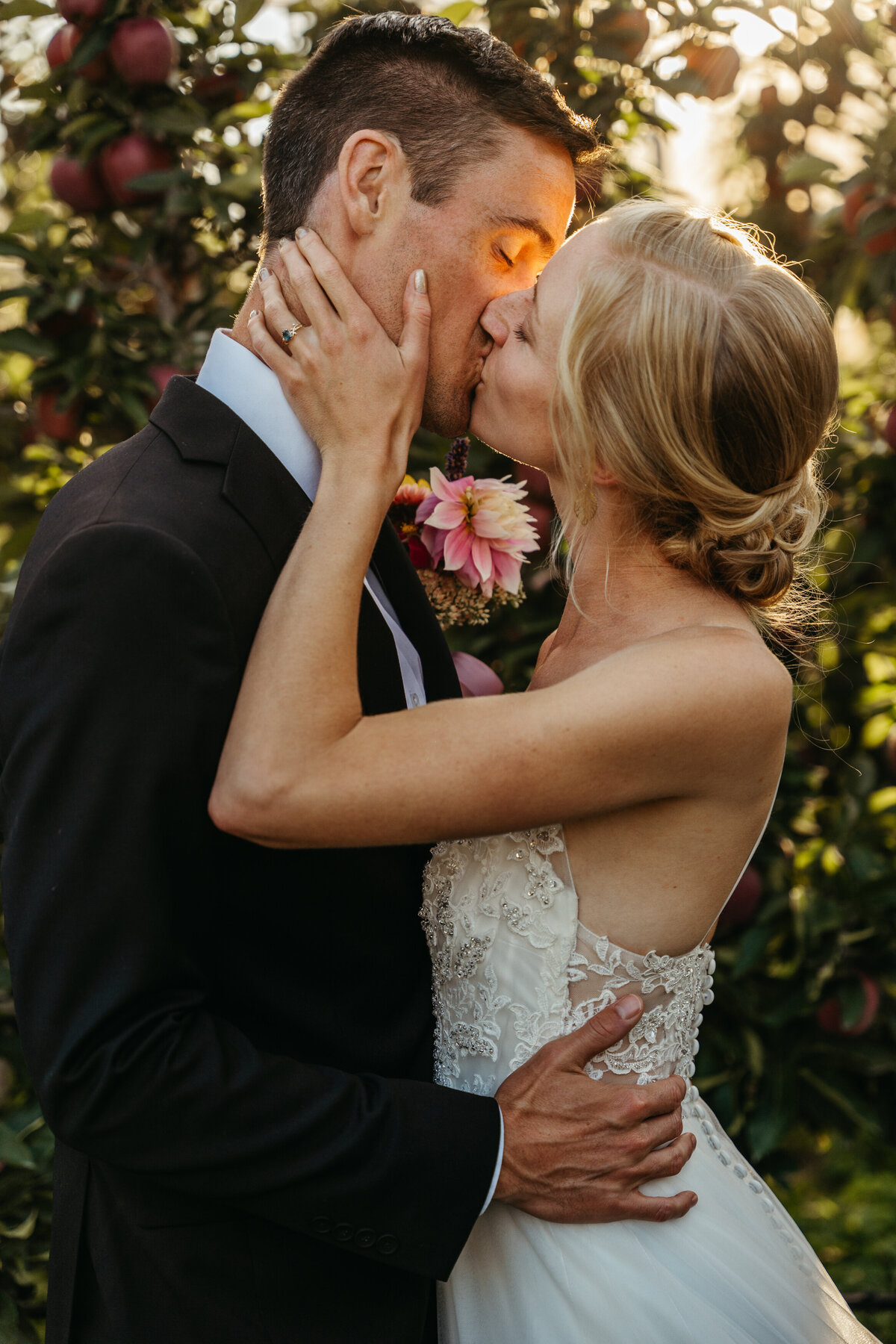 Bride and groom kissing in apple orchard