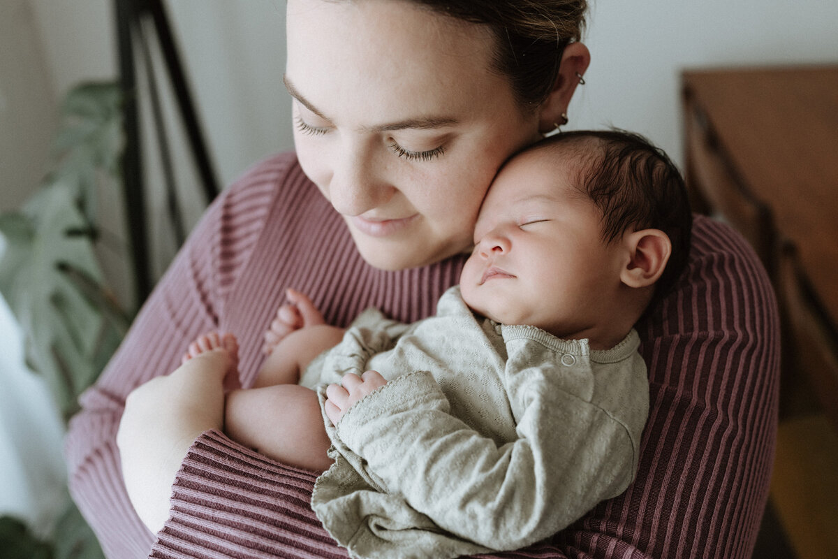 First time mum holds her newborn daughter against her cheek during a relaxed and calm in-home photoshoot in North Brisbane.