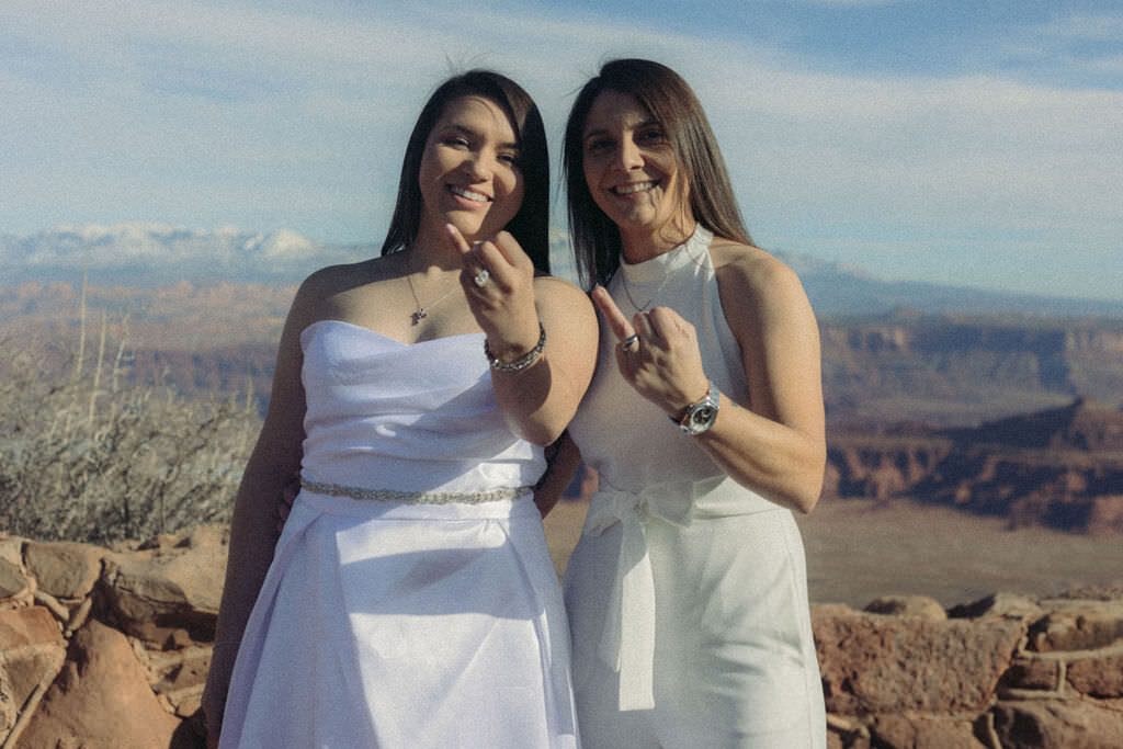 A newlywed couple with their ring fingers up.