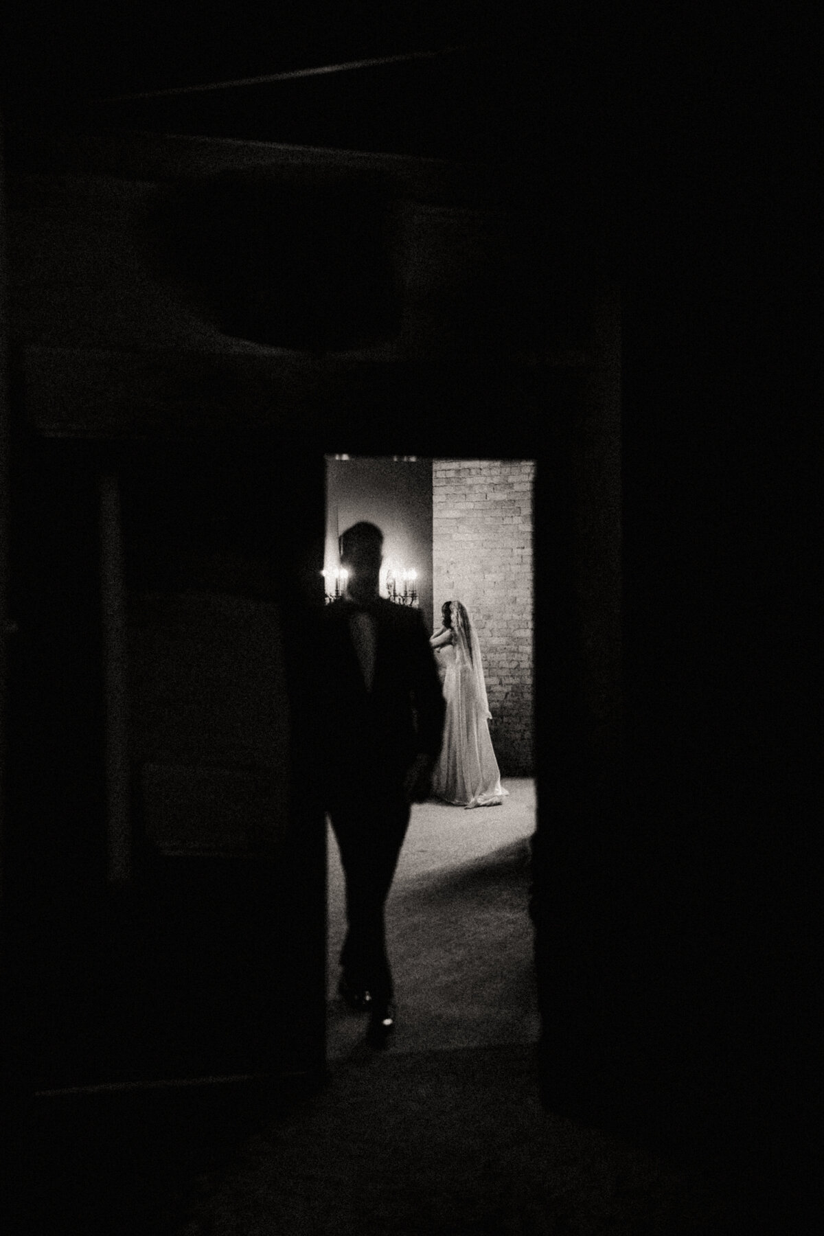Groom watching his bride with finishing touches captured in black and white by Clewell Photography