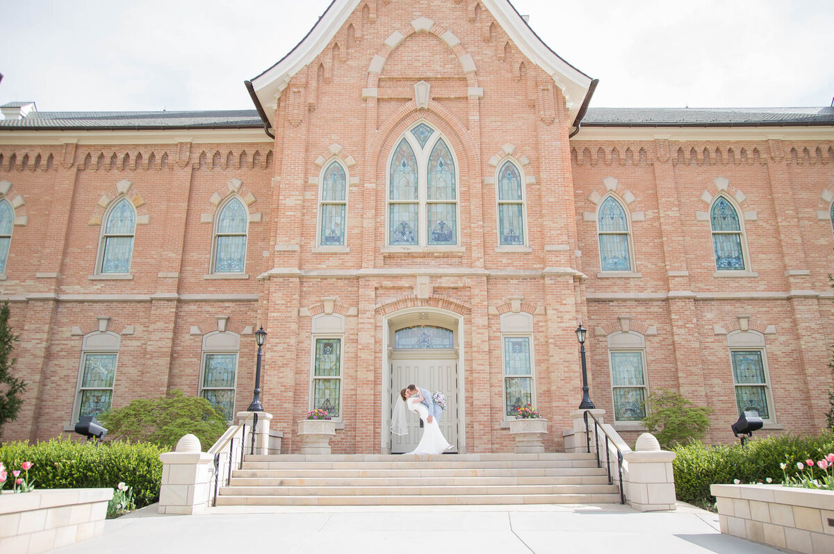 wide view of a wedding couple on the stairs of a brick building