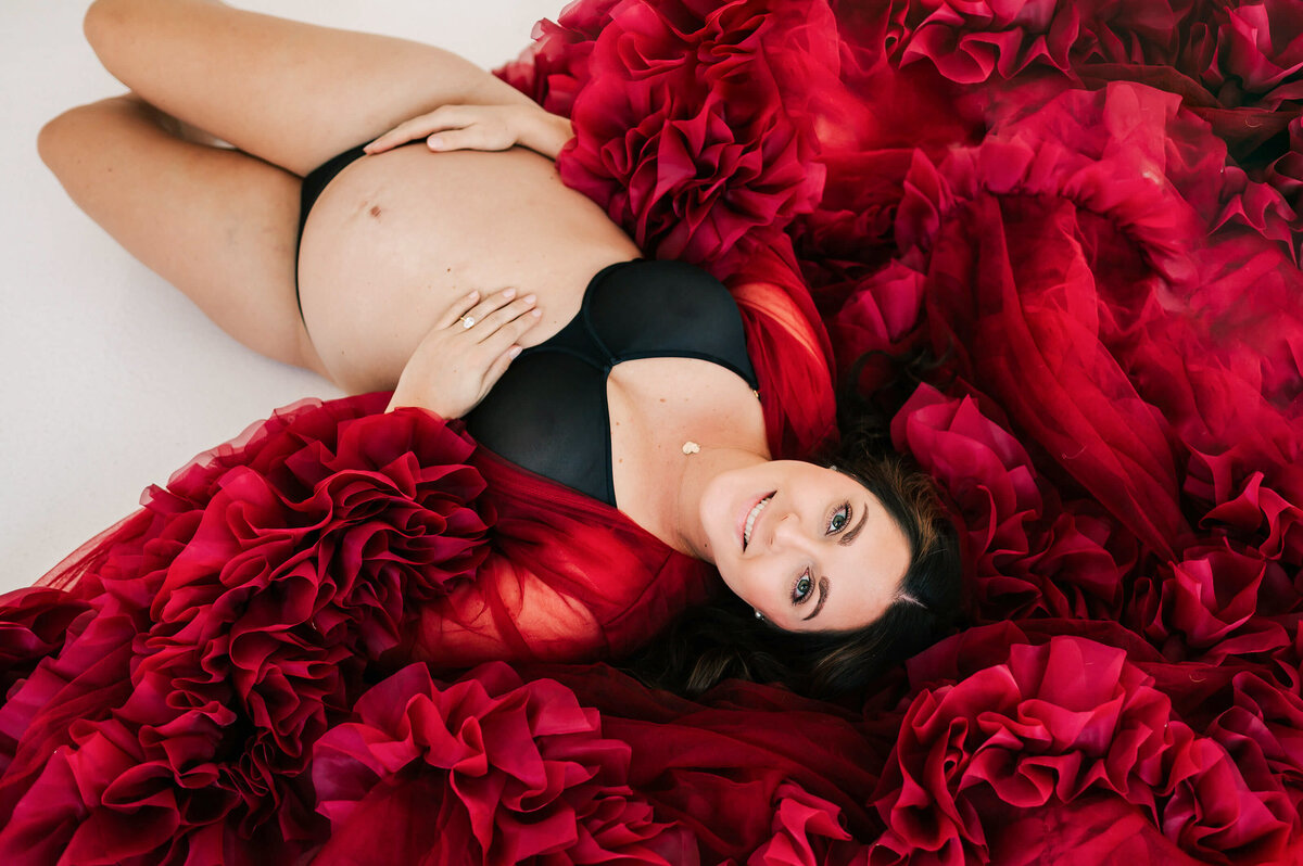 pregnant mom smiling laying on ground in maternity photography studio in Springfield MO