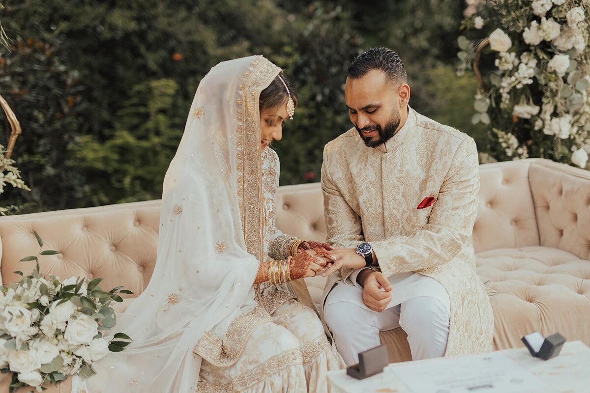 Bride places his ring on her groom's finger during their wedding ceremony.