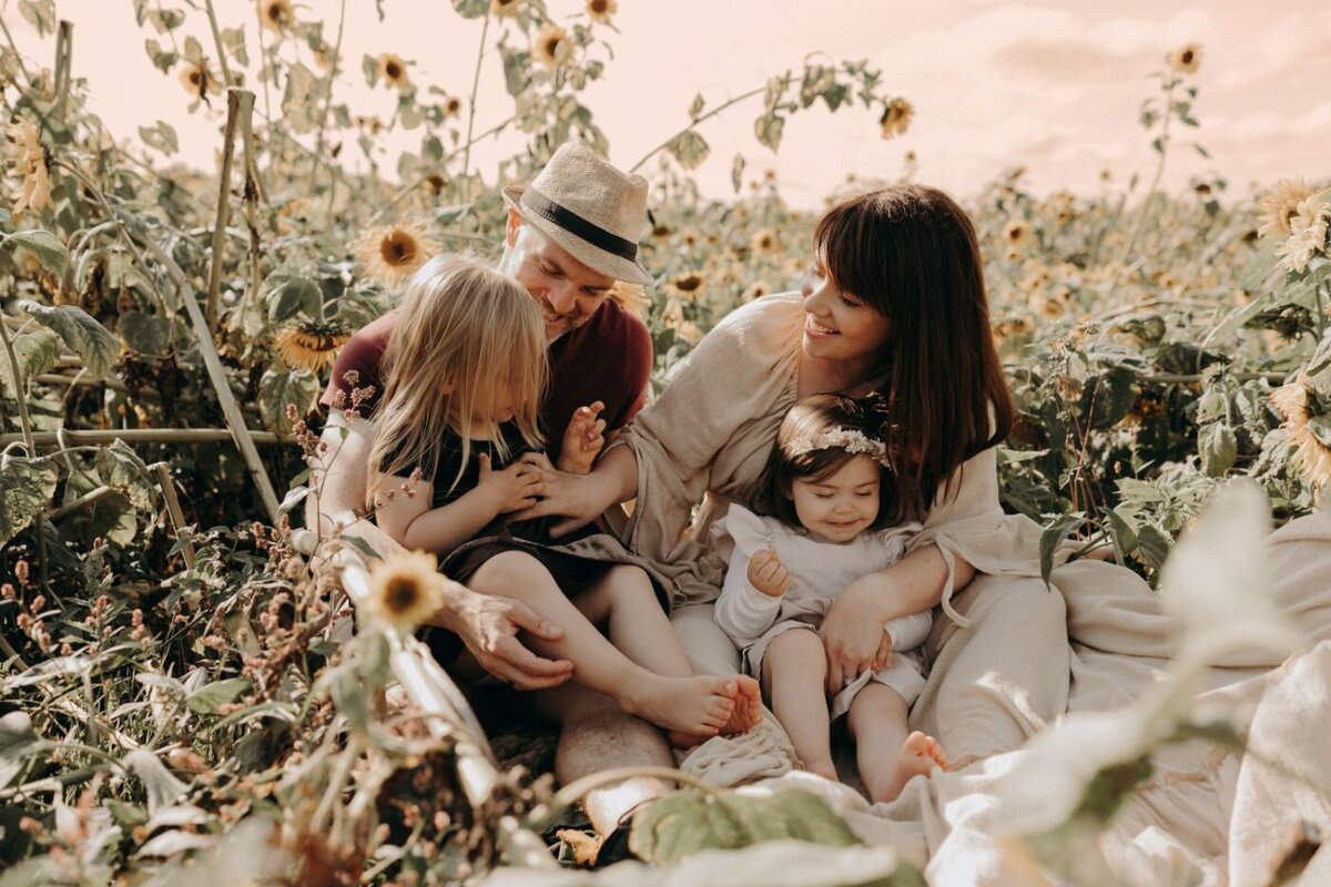 Happy family of four (parents and two daughters) in a sunny sunflower field during a Mullingar photoshoot