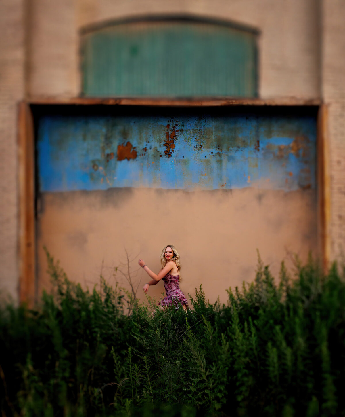 The green weeds and old colorful building frames the jumping senior.