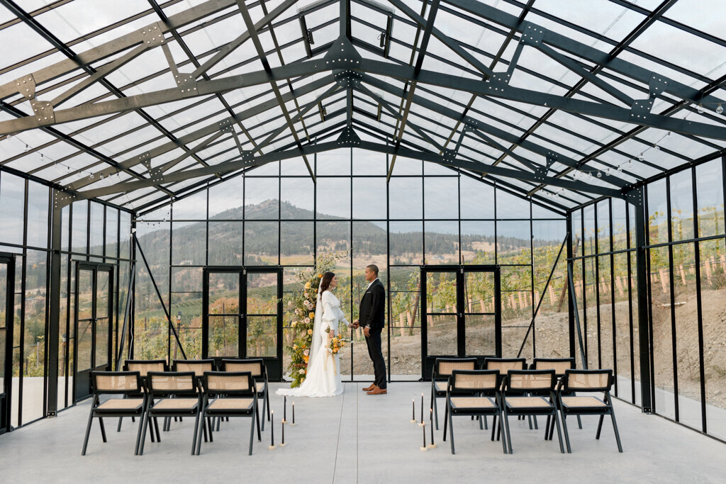 Modern and minimalistic wedding ceremony in The Glasshouse at 99 Rows Venue & Vine, a contemporary and unique wedding venue in Okanagan, BC, featured on the Brontë Bride Vendor Guide.