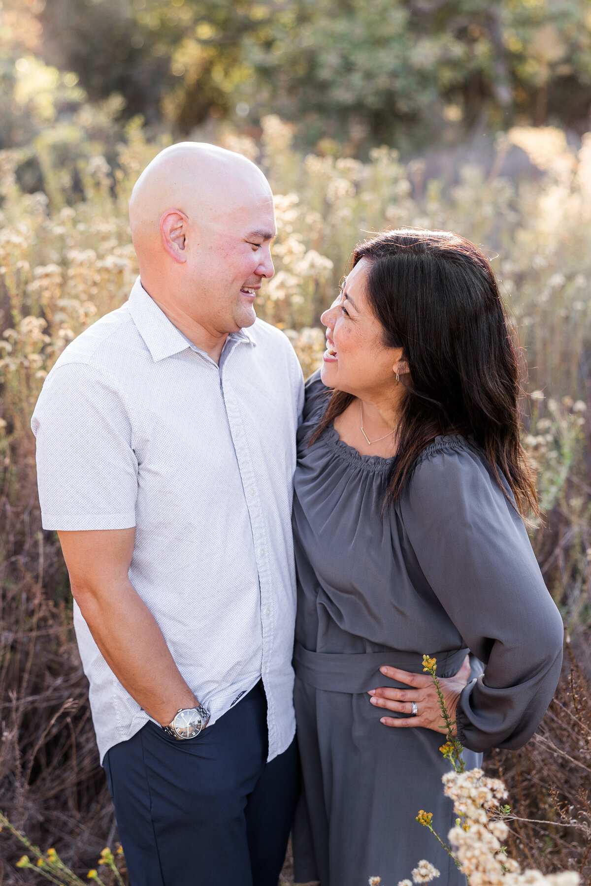 parents smilinng at each other in tall grass field