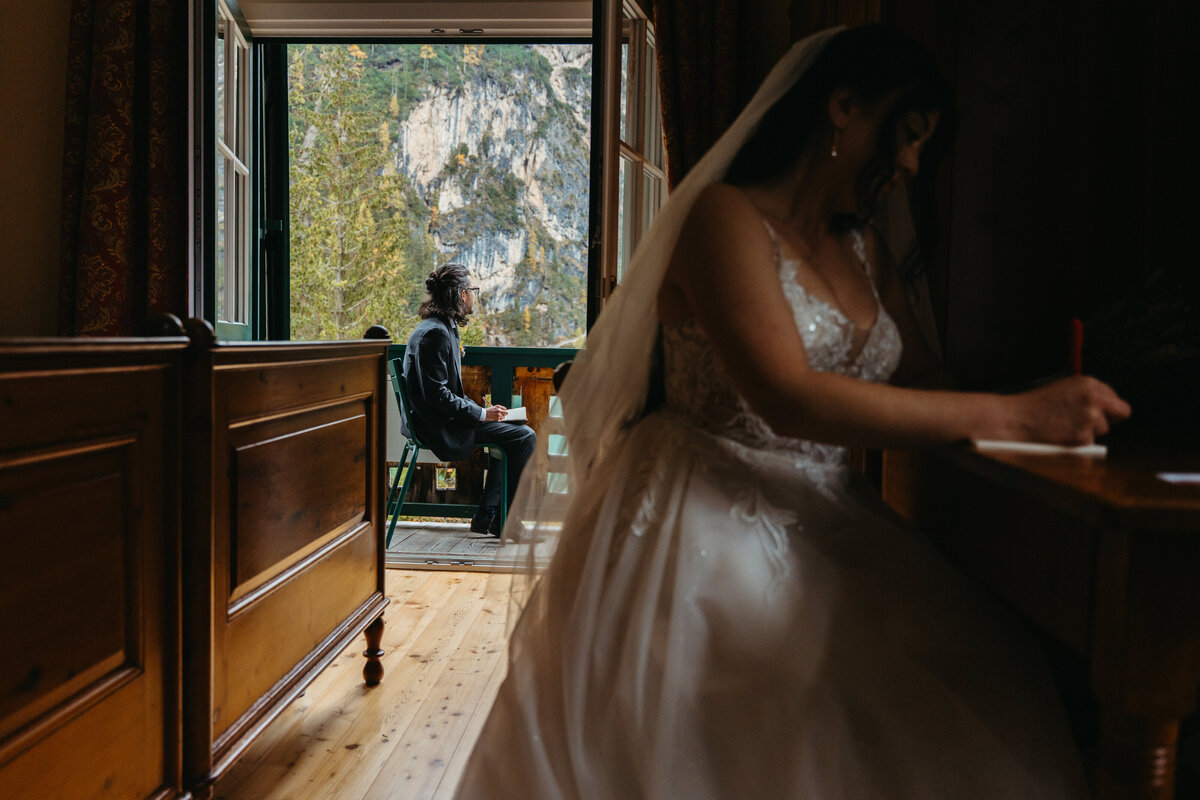 Bride sitting at desk in cabin while writing vows