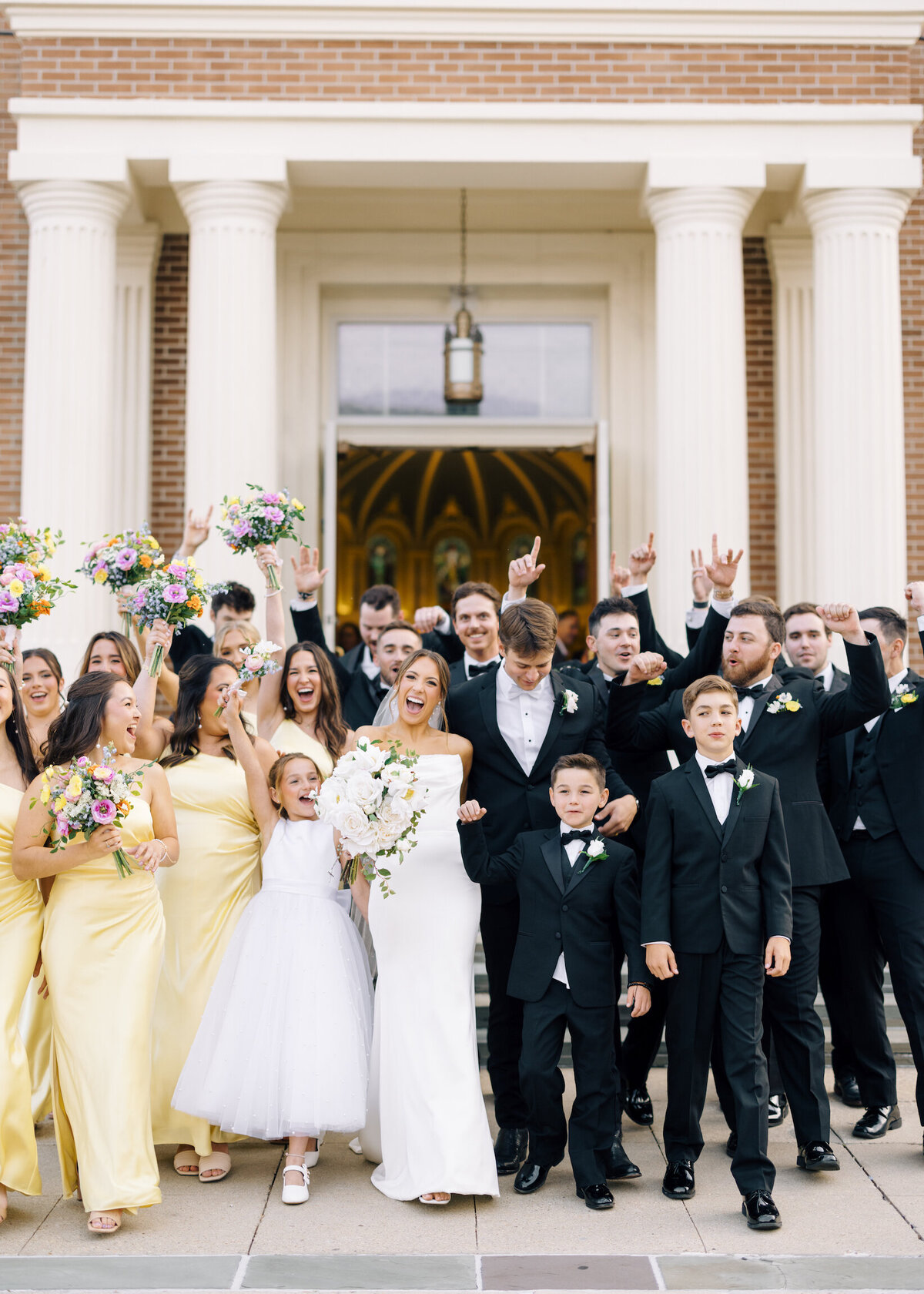 A joyful portrait of the bride and groom surrounded by their wedding party, celebrating together on their special day, beautifully captured on film by Morgan Alysse, Louisiana film photographer.