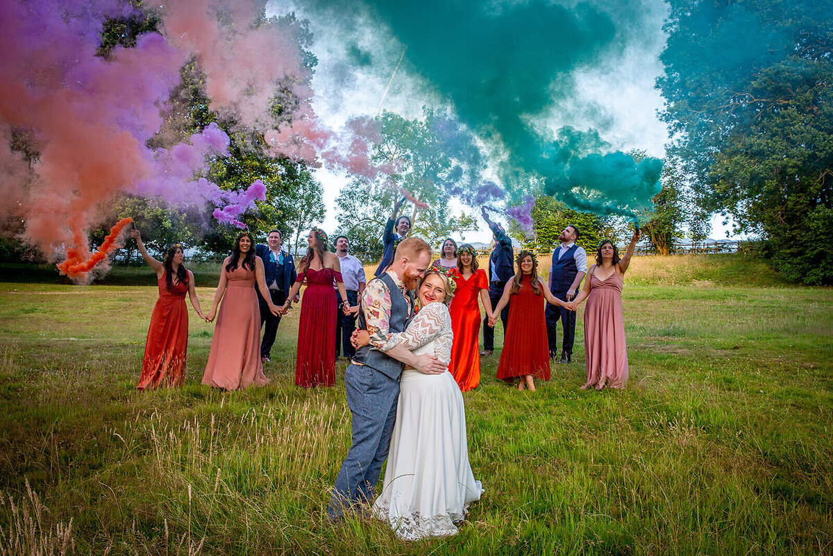 Bride and groom in field with wedding party and coloured  flares. Greenhill Farm