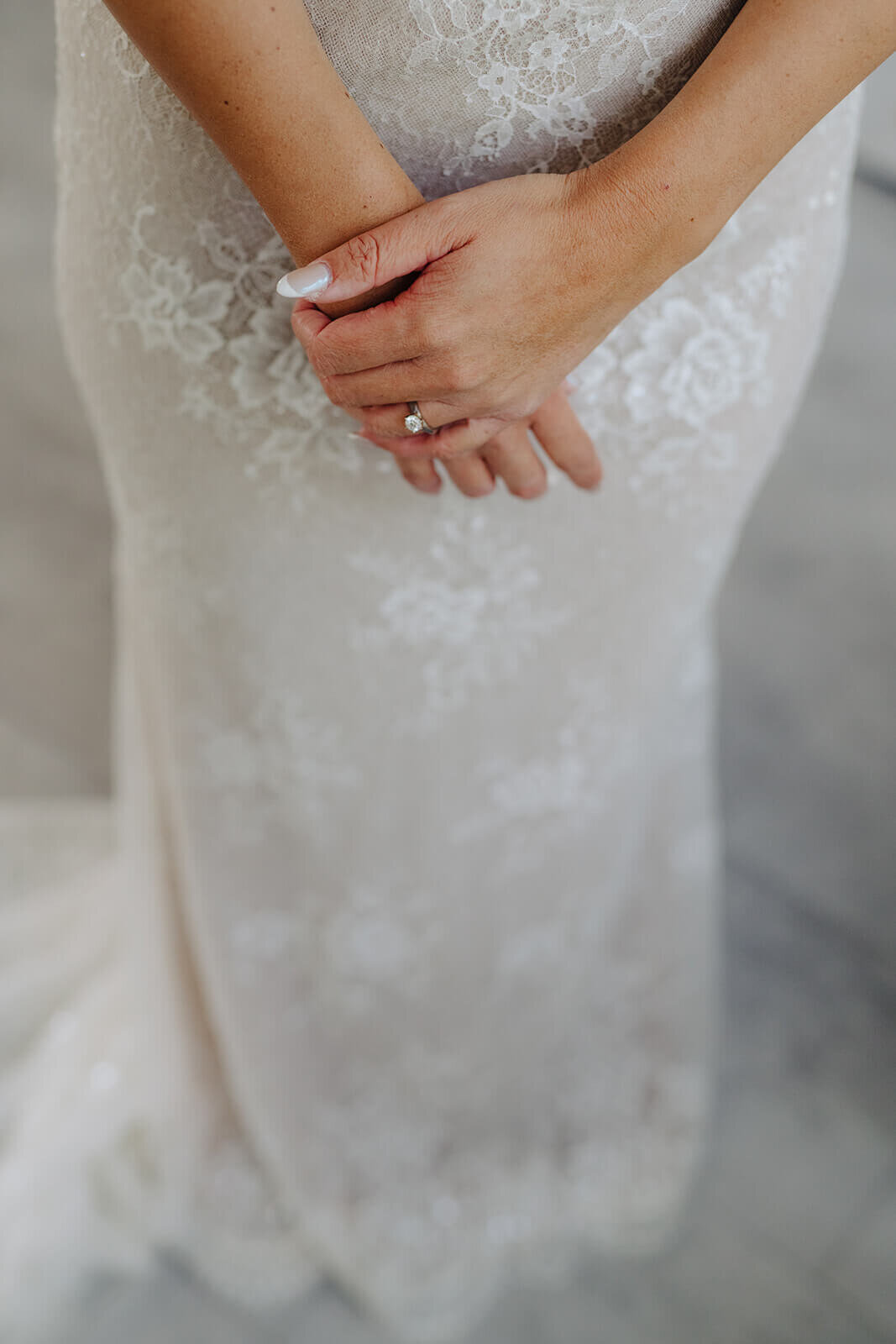 Close up of brides dress with her hands crossed