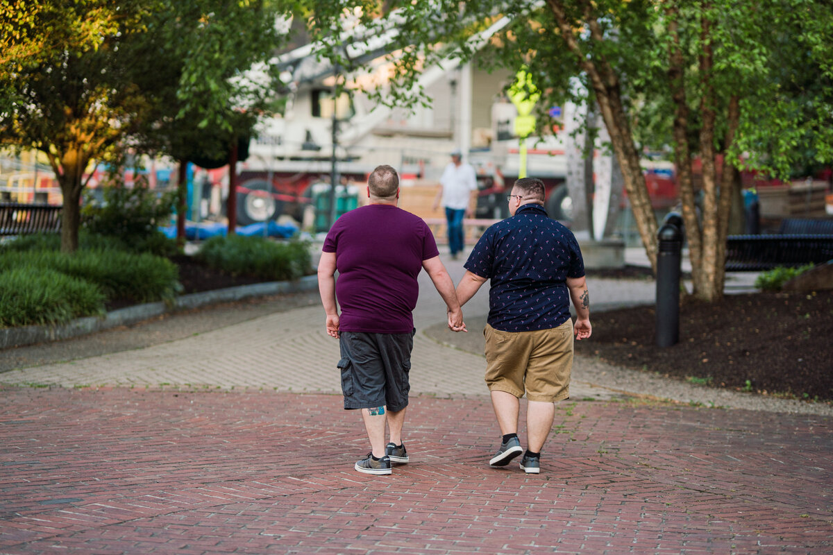 Couple holding hands and walking through downtown Rochester for their engagement session