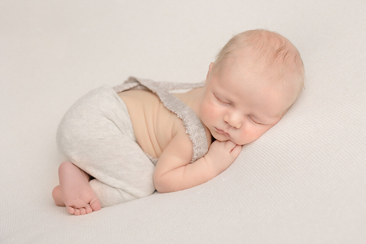 baby boy in overalls sleeping on belly in pdx baby photo session