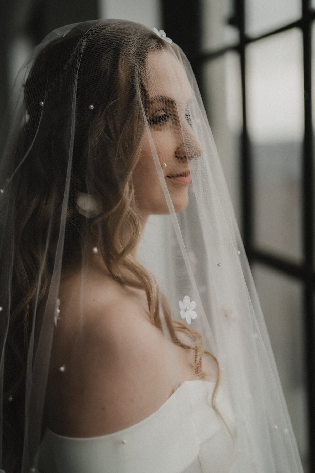 Mariée contemplative regardant à l'extérieur dans une ambiance romantique et mélancolique au Studio Giovanelli.