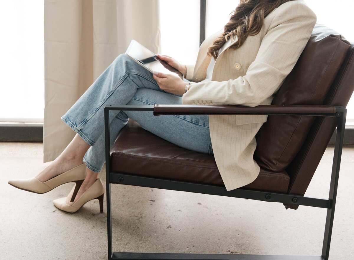 Dallas tax planning expert at Romo CPA Tax + Advisory using an iPad in her office while dressed in jeans and a beige blazer, creating strategic tax plans for clients.