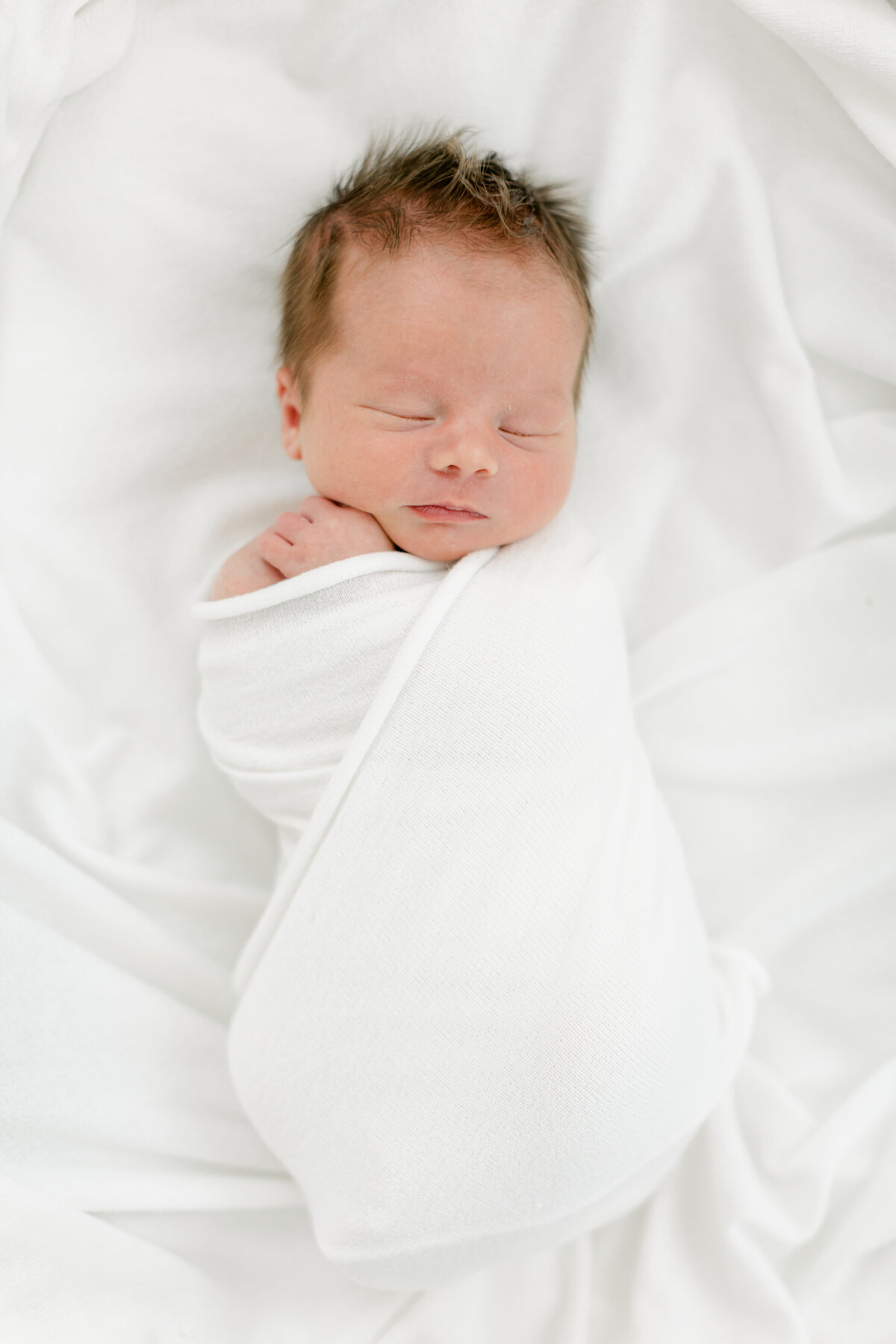 infant baby boy swaddled in a white blanket naturally posed by Philadelphia Newborn Photographer Tara Federico