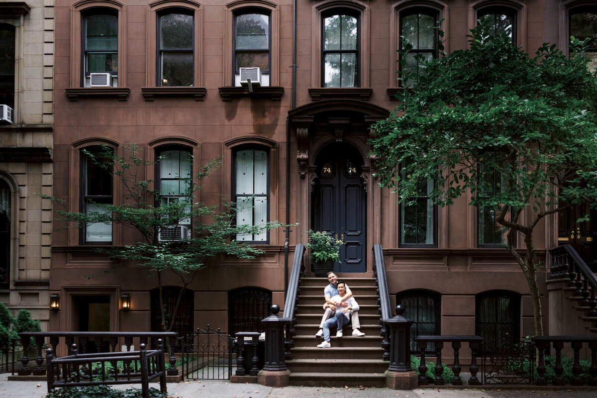 The engaged couple is sitting romantically on the entrance staircase of a house in West Village, NYC. Image by Jenny Fu Studio