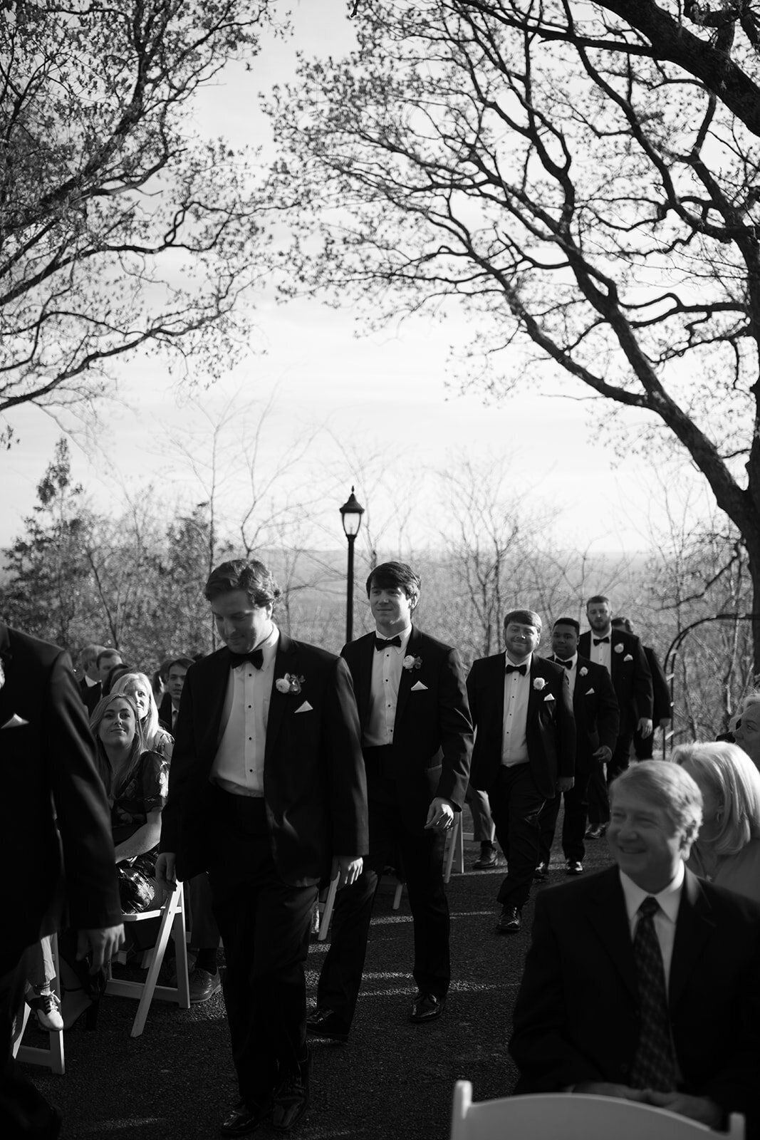 Black and white photo of the groomsmen walking down the aisle during the wedding ceremony at Burritt on the Mountain in Huntsville, Alabama, photographed by Perry Hancock.