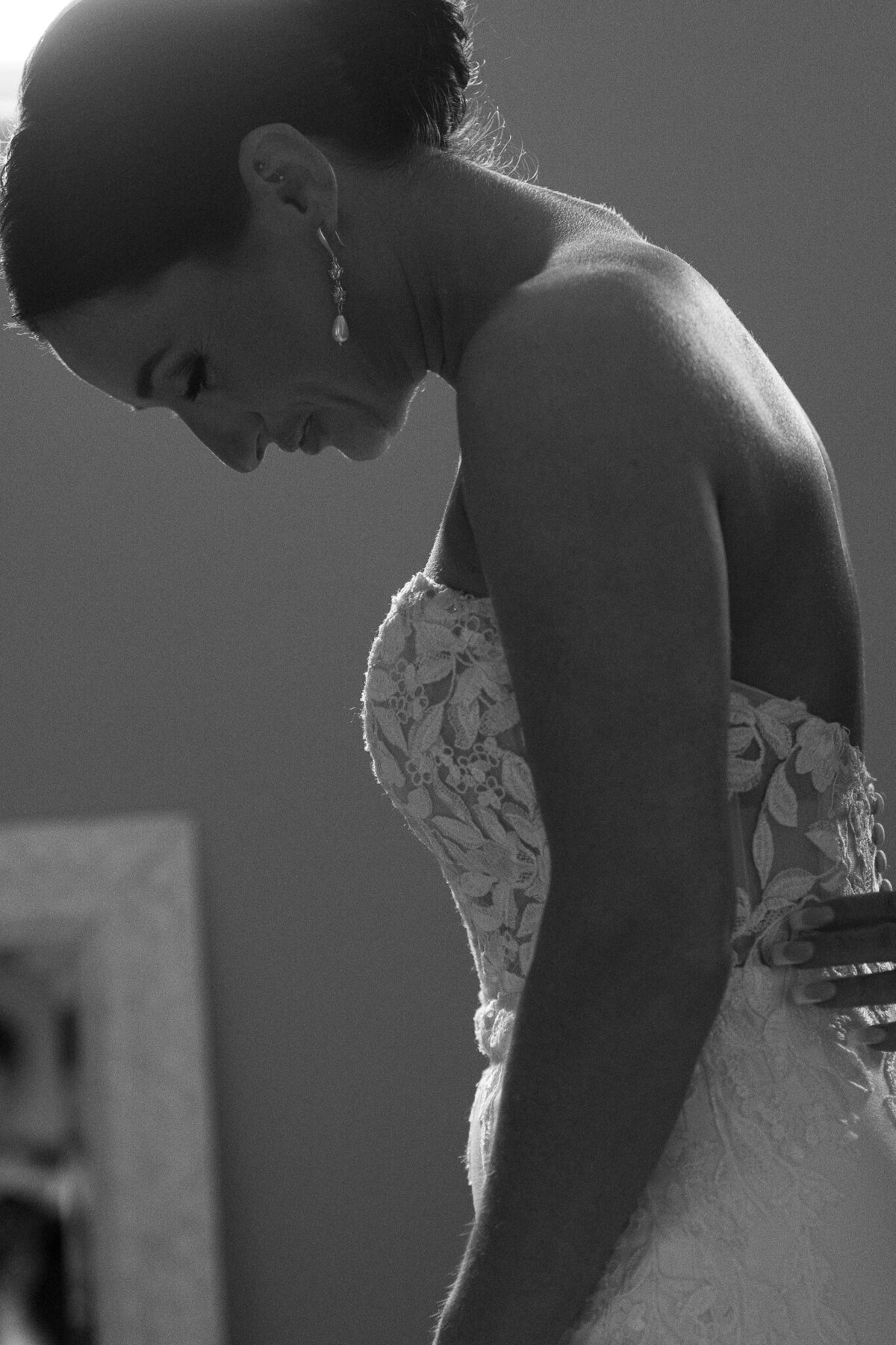 Candid close-up of bride adjusting gown in emotional black and white moment