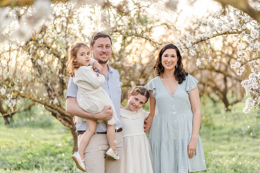 Brisbane family with joyful smiles in the serene ambiance of plum blossoms around them, perfect location for family photos in Brisbane.
