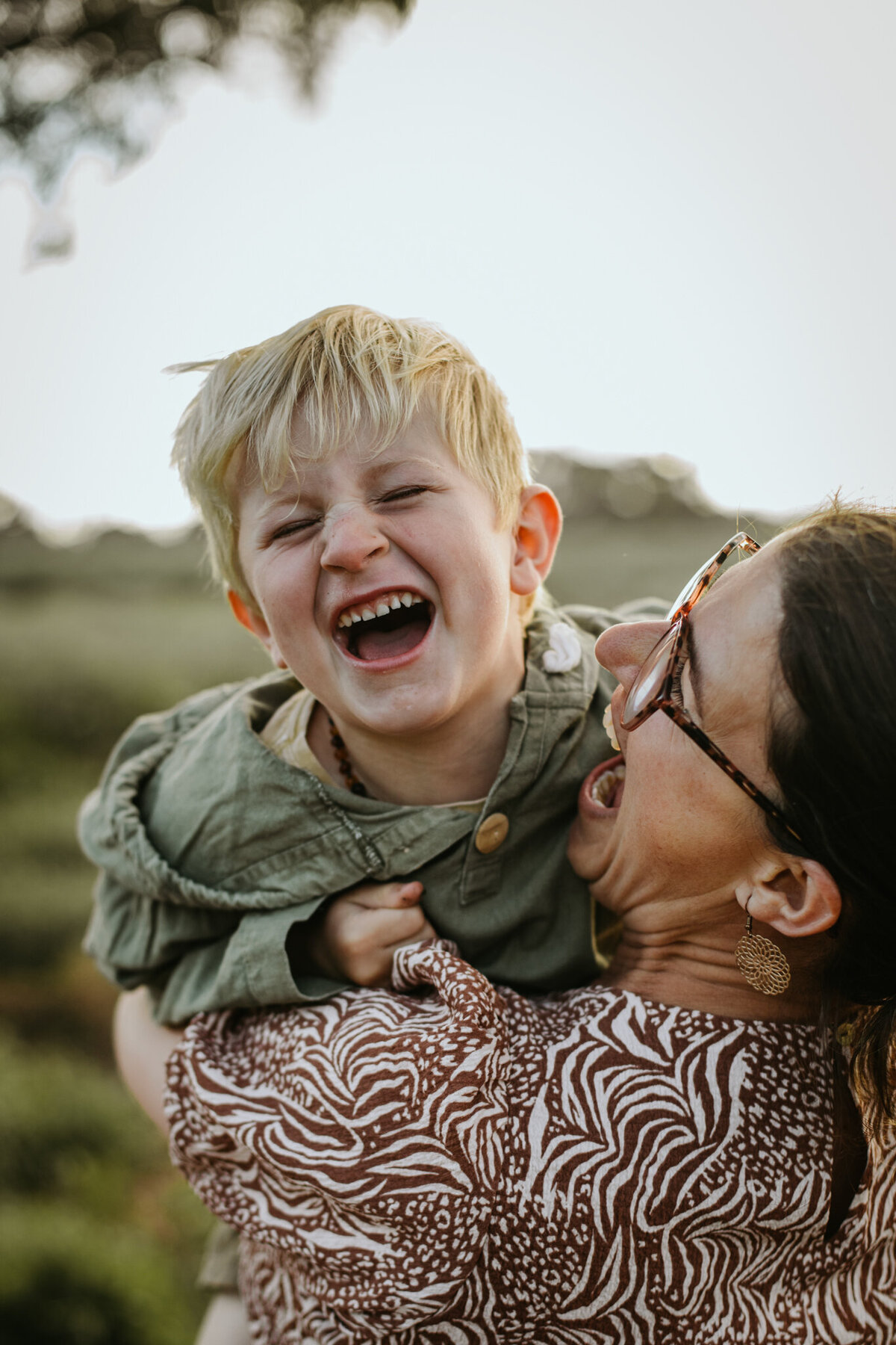 Tender, playful moment of a mom tickling her son, his eyes closed in delight.