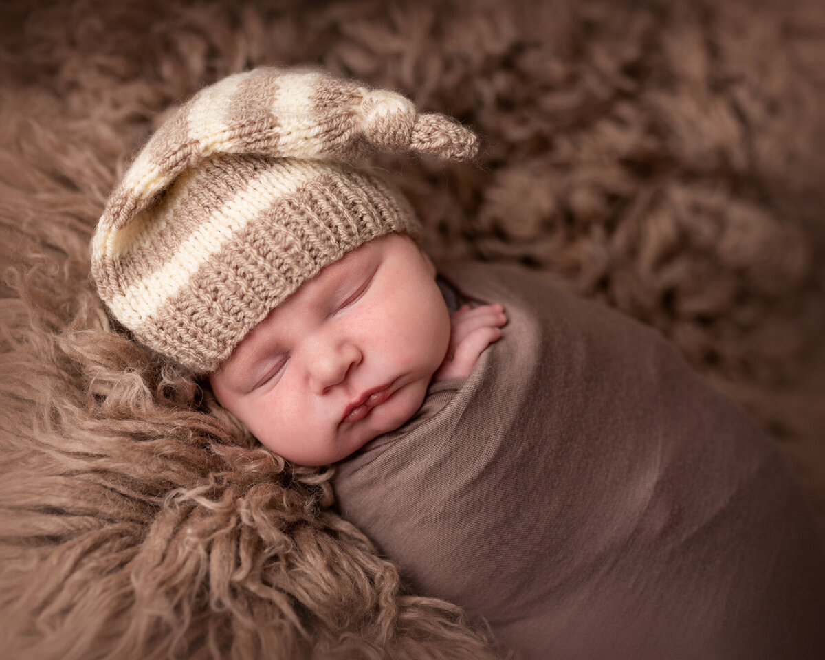 Wrapped newborn in brown furry background by Laura King Photography