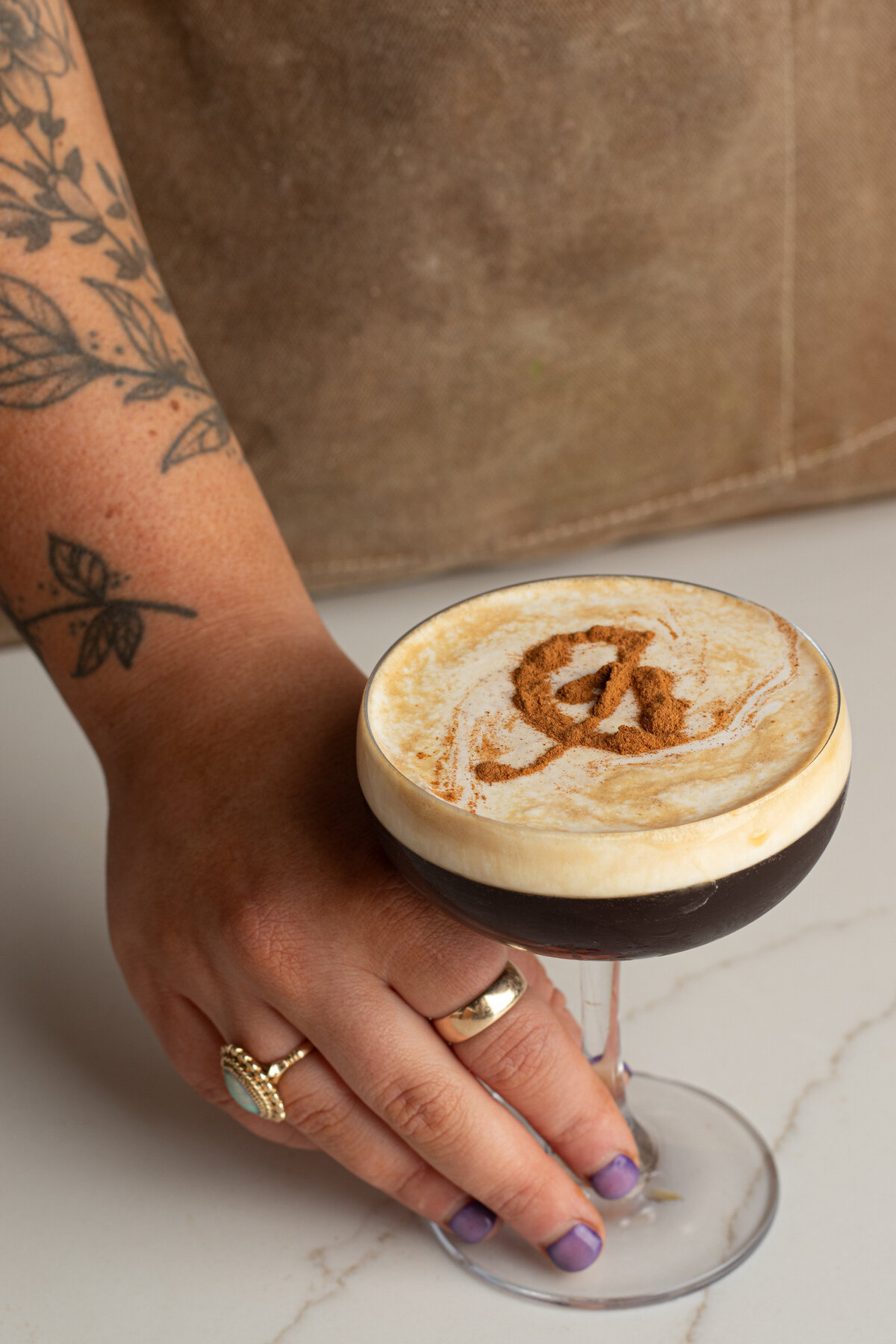 a woman's hand holding a glass with a coffee cocktail in it